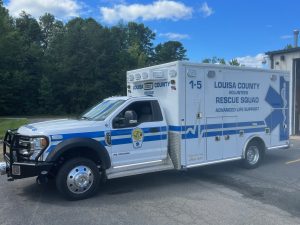A louisa county volunteer rescue squad ambulance parked outdoors, featuring bold blue and white colors with the emblem clearly visible on the side.